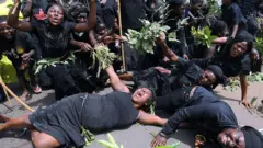 Awọn obinrin to wọ aṣọ dudu n sunkun kikoro, wọn ja ewe dani.
Awọn kan sun silẹ ninu wọn
