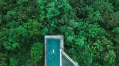Fotografia aérea com drone mostra uma mulher nadando em uma impressionante piscina infinita em Bali.