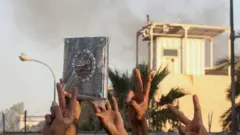 شبان عراقيون يرفعون شارة النصر بأيديهم أثناء تظاهرة أمام السفارة السويدية في بغداد