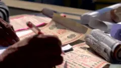 हातमा कलम बोकेर जन्मकुण्डली बनाउँदै एक ज्योतिषी, अगाडि पञ्चाङ्ग पनि देखिन्छ 