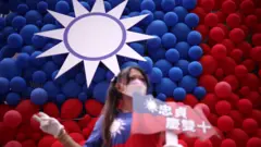 台灣桃園忠貞新村文化園區內一位女士在氣球拼成的青天白日滿地紅旗前拍照（10/10/2023）