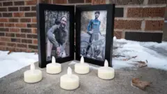 Two framed images show Alex Pretti sitting crouched over by the camera in a wood, and the other holding a bicycle while wearing a helmet and cycling gear, with LED candles placed in front of the frames on the doorstep to Alex Pretti's house in Minneapolis, taken on 26 January.