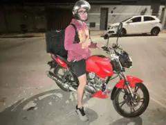 O criador de conteúdo Henrique Batista em cima de uma moto, com capacete e mochila