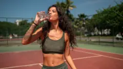 Spor yaparken su içen bir kadın
