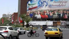 Trânsito em frente a um outdoor mostrando vários iranianos, incluindo militares e o Ministro das Relações Exteriores iraniano Abbas Araghchi (3º à direita) saudando e uma mensagem dizendo: "Todos nós somos soldados do Irã", na praça Vali Asr em Teerã