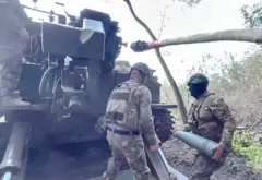 Два российских артиллериста заряжают гаубицу