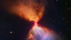 Nuvens rodopiantes em tons de laranja e azul se espalham acima e abaixo de um centro brilhante, com um pano de fundo escuro de estrelas distantes visíveis.