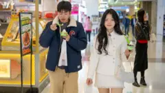 Un chico y una chica pasean por un centro comercial en China.