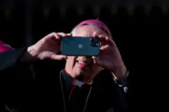 Um bispo tira uma foto com um celular ao final da audiência geral semanal do papa Leão