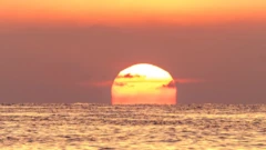 Red sun setting over the sea, orange skies