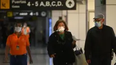 Personas con mascarillas en el aeropuerto de El Salvador.
