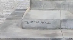 As letras B A N K S Y rabiscadas na base de um pedestal de pedra