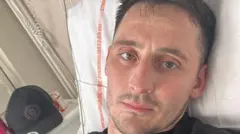 Sam Davies lying in a hospital bed