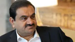 A close-up of Gautam Adani's face wearing a white shirt and black suit jacket during a 2024 interview with Bloomberg news