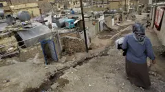 زنی در یک منطقه حاشیه شهری با خانه هایی که روبروی او است