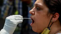 ஒரு பெண்ணிடம் இருந்து தொண்டைத் தடவல் மாதிரி எடுக்கும் சுகாதாரப் பணியாளர்