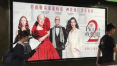 两位年轻人走过《穿Prada的恶魔2》海报