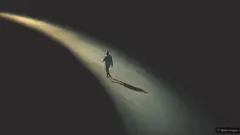 Un homme marchant seul sur une route faiblement éclairée.