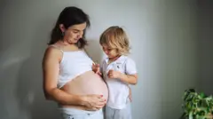 Mulher grávida ao lado de uma criança já mais velha