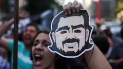 Um homem segura uma máscara de Daniel Vorcaro em uma manifestação contra a corrupção.