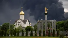 Церковь и золоченая фигура на фоне клубов черного дыма от горящего НПЗ в Москве (18 июля 2026 года)