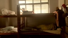 Quatro camas de beliche; uma delas tem pessoa dormindo