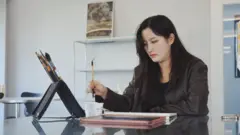 A tatuadora Narr pintando em uma mesa