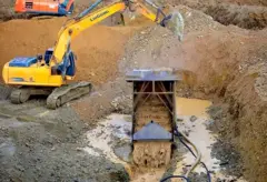 በወርቅ ቁፋሮ ላይ ያለ ስካቫተረ ተሽከርካሪ እና የማጠቢያ ማሽን