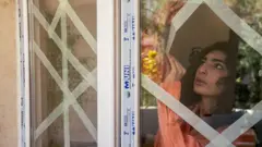 Жінка в Тегерані заклеює вікна клейкою стрічкою від обстрілів