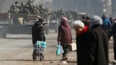 Abasirikare bashyigikiye Uburusiya bari mu bifaru banyura ku baturage mu mujyi uri ku cyambu wa Mariupol mu majyepfo ya Ukraine, uri mu gihirahiro