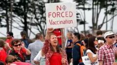 Жінка з плакатом "Ні примусовій вакцинації" на протесті