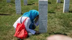 Una mujer bosnia junto a la tumba de un familiar en el cementerio donde reposan las víctimas de la masacre de Srebrenica.