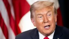 ダークスーツに赤いネクタイのトランプ氏が口を開いている