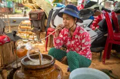 Một người phụ nữ ngồi xổm uống rượu cần ở Kon Tum 