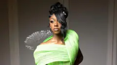 Une image en gros plan de Laniyah Belcarist portant une robe vert clair.