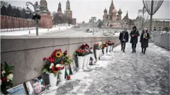 Люди возлагают цветы к портрету Немцова в центре Москвы