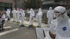 Men in protective clothing conduct coronavirus tests in Beijing