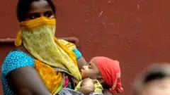 కరోనావైరస్ లాక్‌డౌన్‌లో తన బిడ్డను తీసుకెళ్తున్న మహిళ