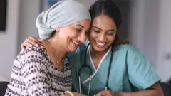 Una enfermera abraza a una paciente con cáncer