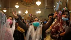 Women wear face masks as they pray during a Christmas Eve Mass in St Andrew's Church in Karachi, Pakistan. Photo: 24 December 2020