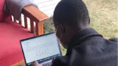 David, Mwandishi wa kitaaluma wa Kenya akiendelea na kazi katika laptop yake.