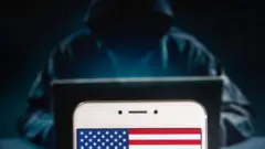 Силуэт хакера на фоне смартфона с американским флагом