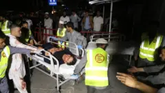 Afghan health workers carry a wounded man into the hospital after the attack