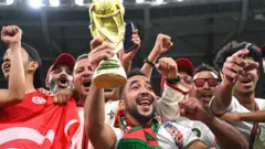مشجعون مغاربة يحملون نسخة طبق الأصل من كأس العالم في قطر