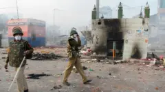 Policemen stand on a vandalised road following clashes between supporters and opponents of a new citizenship law, at Bhajanpura area of New Delhi on February 24, 2020, ahead of US President arrival in New Delhi.