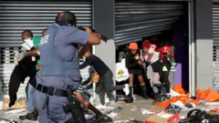 A member of the South African Police Forces tries to control looting during protests in Durban, South Africa, 12 July 2021.