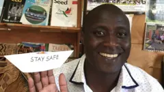 Peter Tabichi with paper boat wey im build