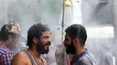 बग़दाद में दो लोग शावर के नीचे खड़े हो कर पसीना सुखा रहे हैं.