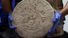 Рабочий экспедиции показывает находку на пресс-конференции