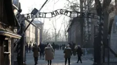 People walking through the infamous gate at Auschwitz, reading Arbeit Macht Frei - or work sets you free. File photo